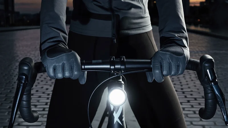 Illustrierte behandschuhte Hände am Lenker mit eingeschaltetem Licht in der Dämmerung
